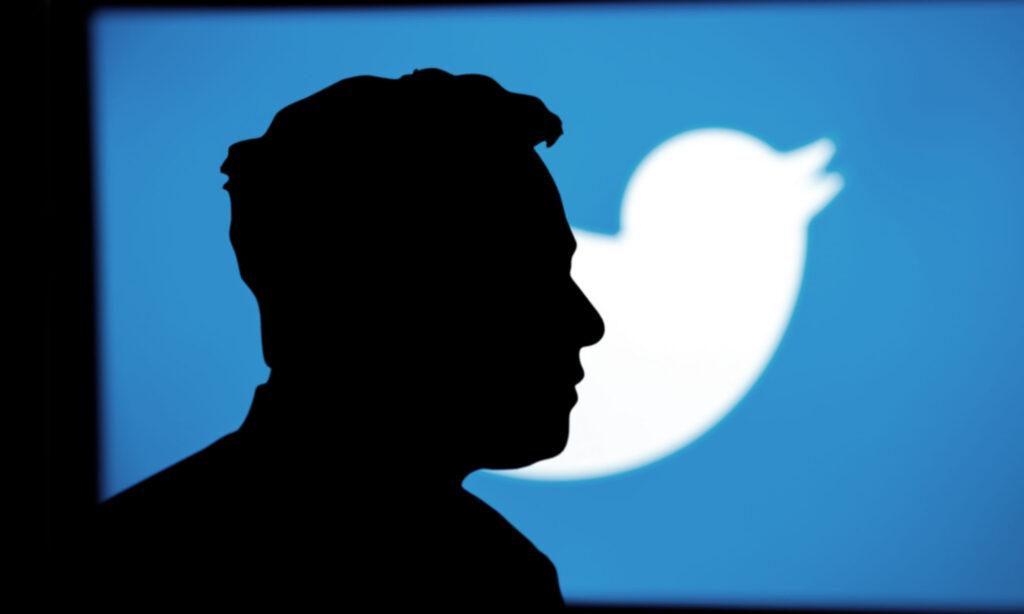 A silhouette portrait of new Twitter CEO, Elon Musk, stands against a background of the Twitter logo.