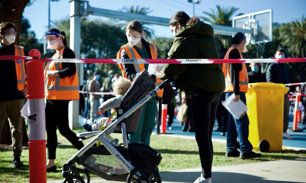 A mother with her child wait outside a busy queue at a vaccination clinic in St Kilda, Melbourne. 
